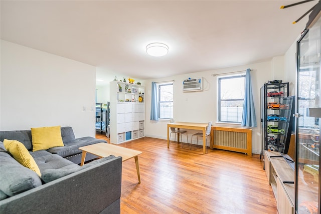 living room with light wood-type flooring, radiator heating unit, and a wall unit AC