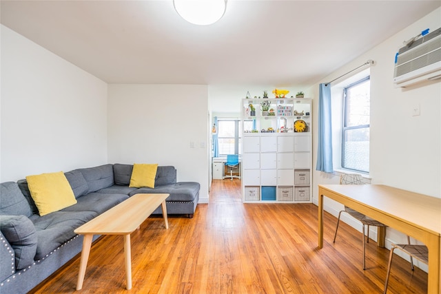 living room with light hardwood / wood-style flooring and a wall mounted air conditioner