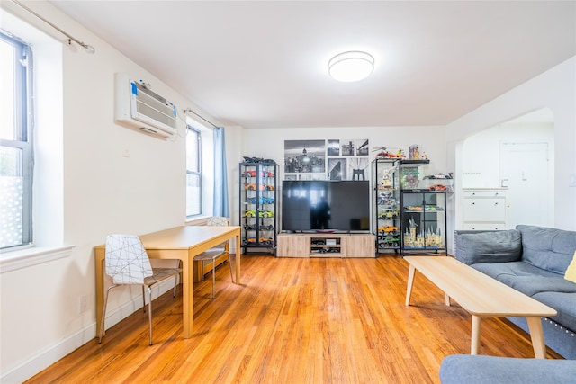 living room featuring wood-type flooring and an AC wall unit