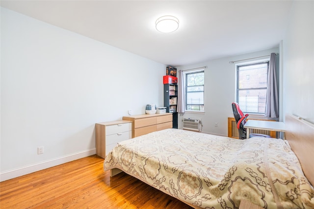 bedroom with a wall mounted AC and light hardwood / wood-style flooring