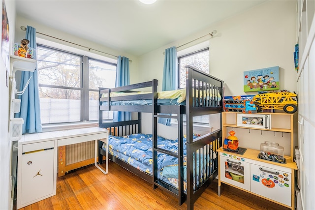 bedroom featuring wood-type flooring, radiator, and multiple windows