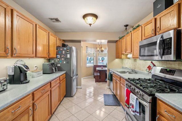 kitchen with sink, stainless steel appliances, a chandelier, decorative backsplash, and light tile patterned floors