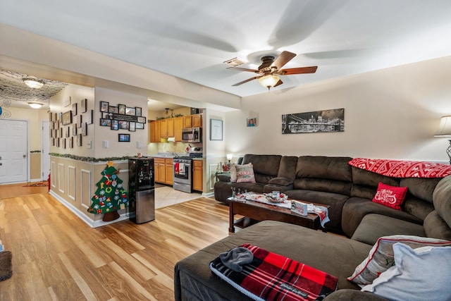 living room featuring ceiling fan and light hardwood / wood-style flooring