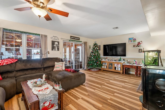 living room with a wealth of natural light, light hardwood / wood-style flooring, and ceiling fan