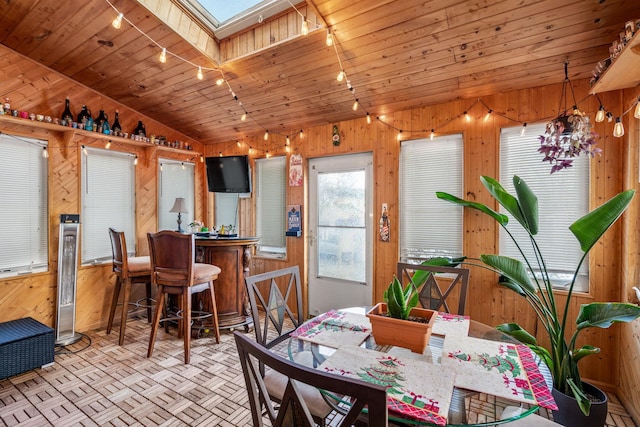 dining space with lofted ceiling with skylight, wooden walls, and wooden ceiling