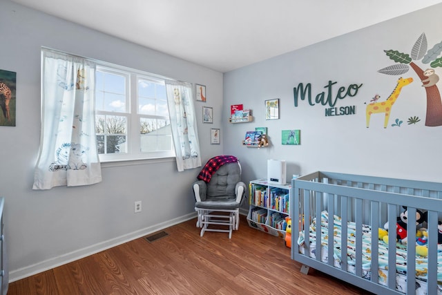 bedroom featuring wood-type flooring and a crib