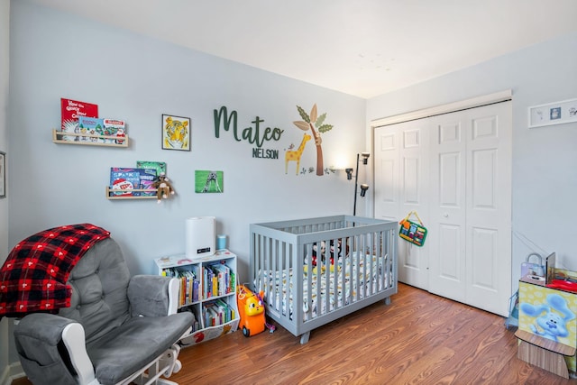 bedroom featuring a closet, a nursery area, and hardwood / wood-style flooring