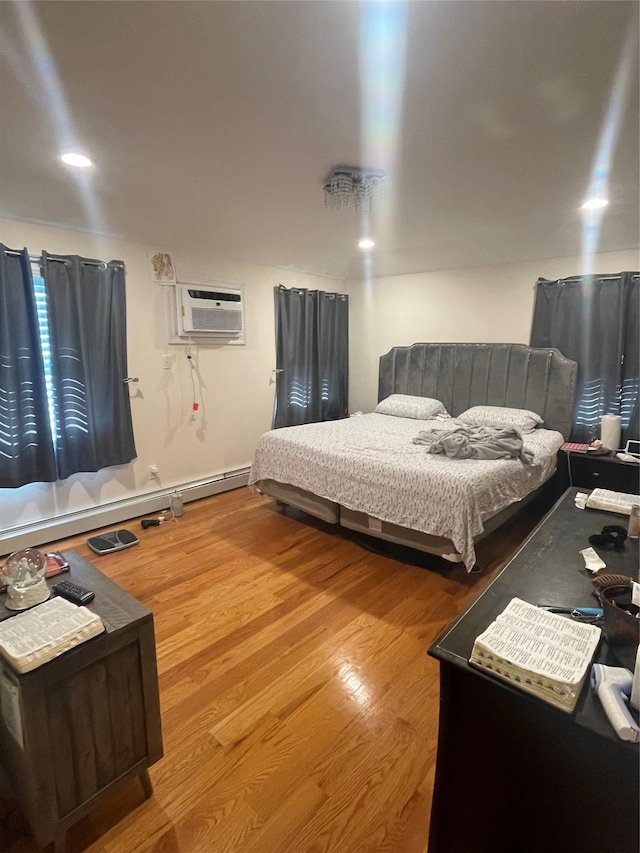 bedroom featuring wood-type flooring, a wall unit AC, and a baseboard heating unit