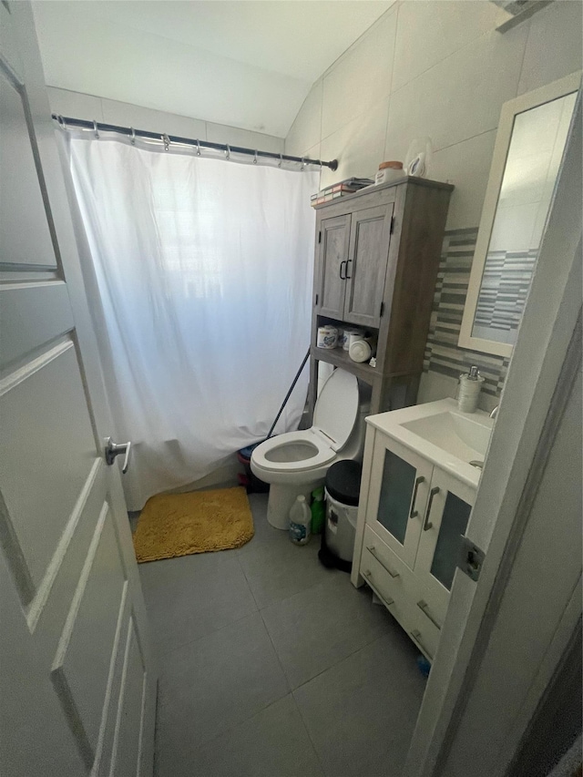 bathroom with toilet, lofted ceiling, tile patterned floors, a shower with curtain, and vanity