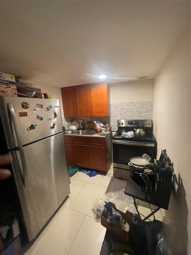 kitchen featuring light tile patterned floors, backsplash, appliances with stainless steel finishes, and sink