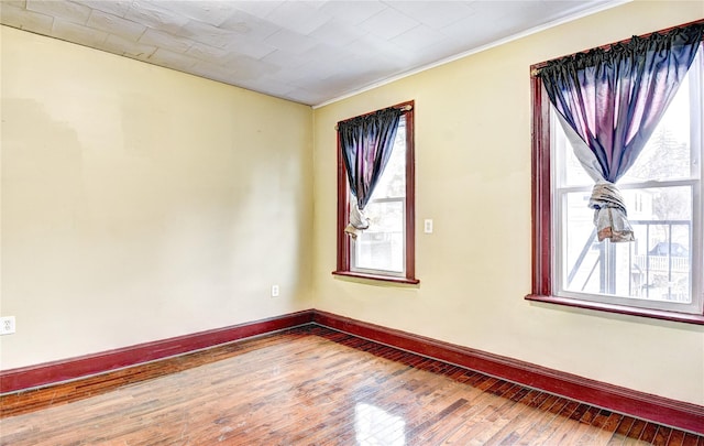 empty room featuring crown molding and wood-type flooring