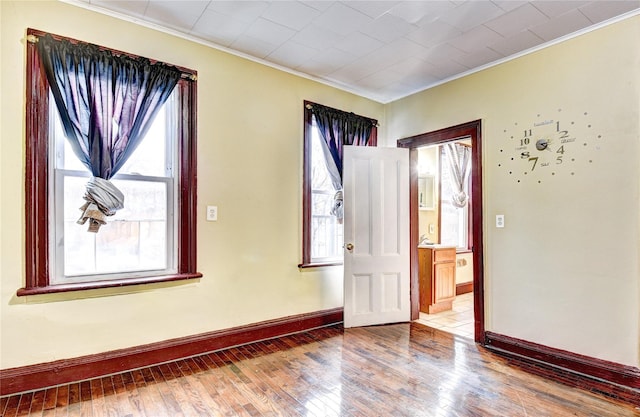 spare room featuring ornamental molding, a healthy amount of sunlight, and hardwood / wood-style flooring