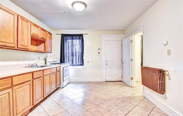 kitchen with sink, light tile patterned floors, and white stove