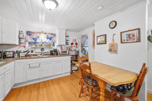 kitchen featuring wooden ceiling, sink, light hardwood / wood-style flooring, decorative light fixtures, and white cabinetry