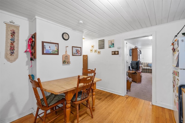 dining space with ornamental molding, light wood-type flooring, and wooden ceiling