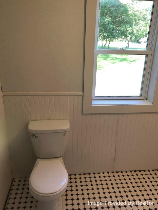 bathroom with wood walls and toilet