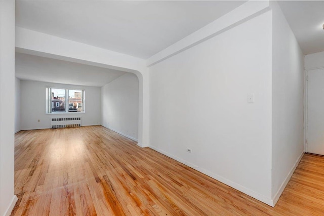 empty room with radiator heating unit and light hardwood / wood-style flooring