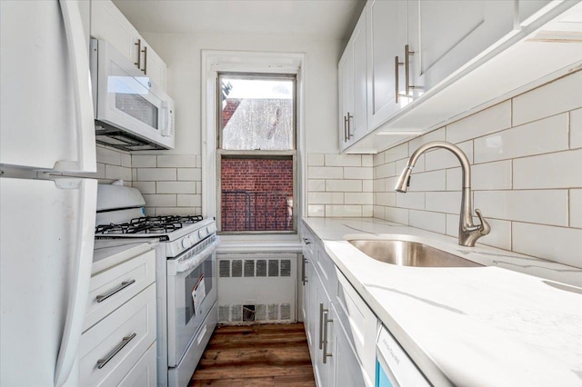 kitchen featuring light stone countertops, radiator heating unit, dark hardwood / wood-style flooring, white appliances, and white cabinets