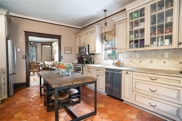 kitchen featuring pendant lighting, cream cabinets, decorative backsplash, ornamental molding, and appliances with stainless steel finishes