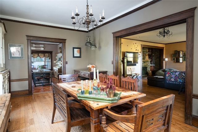 dining space featuring a chandelier, light wood-style flooring, crown molding, and baseboards