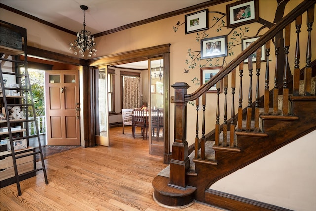 entryway featuring a notable chandelier, stairs, crown molding, and wood finished floors