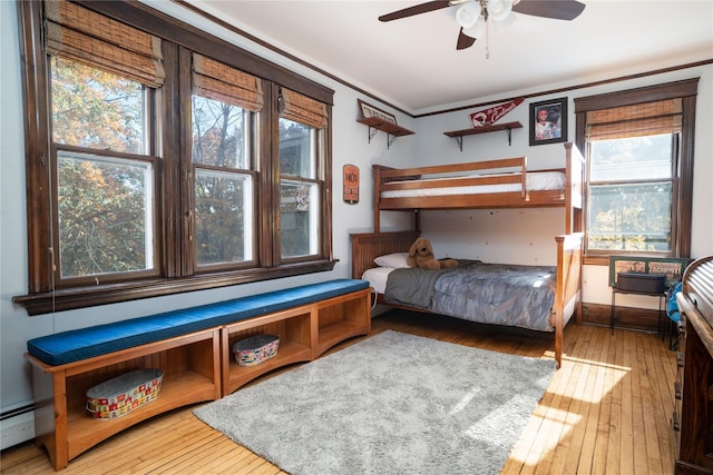 bedroom with hardwood / wood-style floors, a baseboard heating unit, and multiple windows
