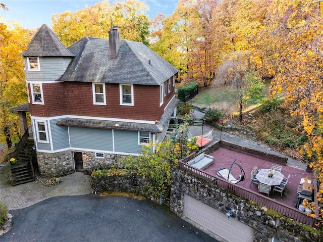 exterior space featuring a chimney, roof with shingles, stairway, and stone siding