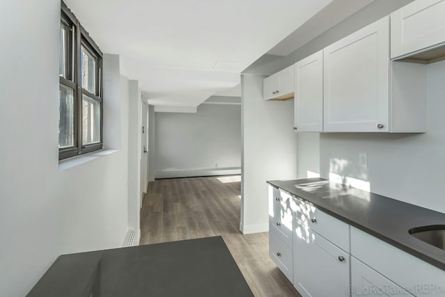 kitchen featuring white cabinets, light wood-type flooring, and a baseboard radiator