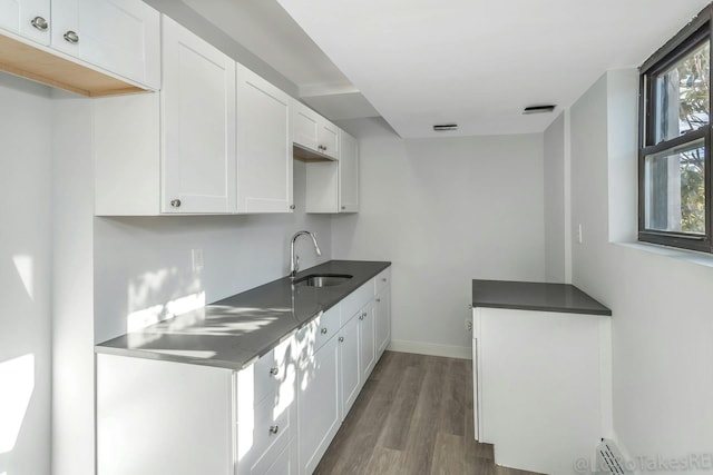 kitchen featuring dark hardwood / wood-style flooring, white cabinetry, sink, and baseboard heating