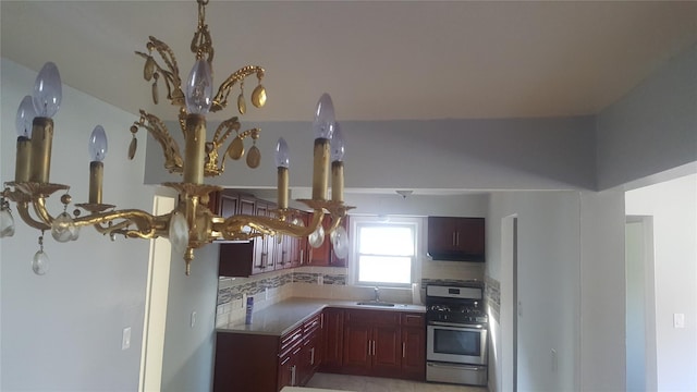 kitchen featuring sink, stainless steel gas range, tasteful backsplash, kitchen peninsula, and a chandelier