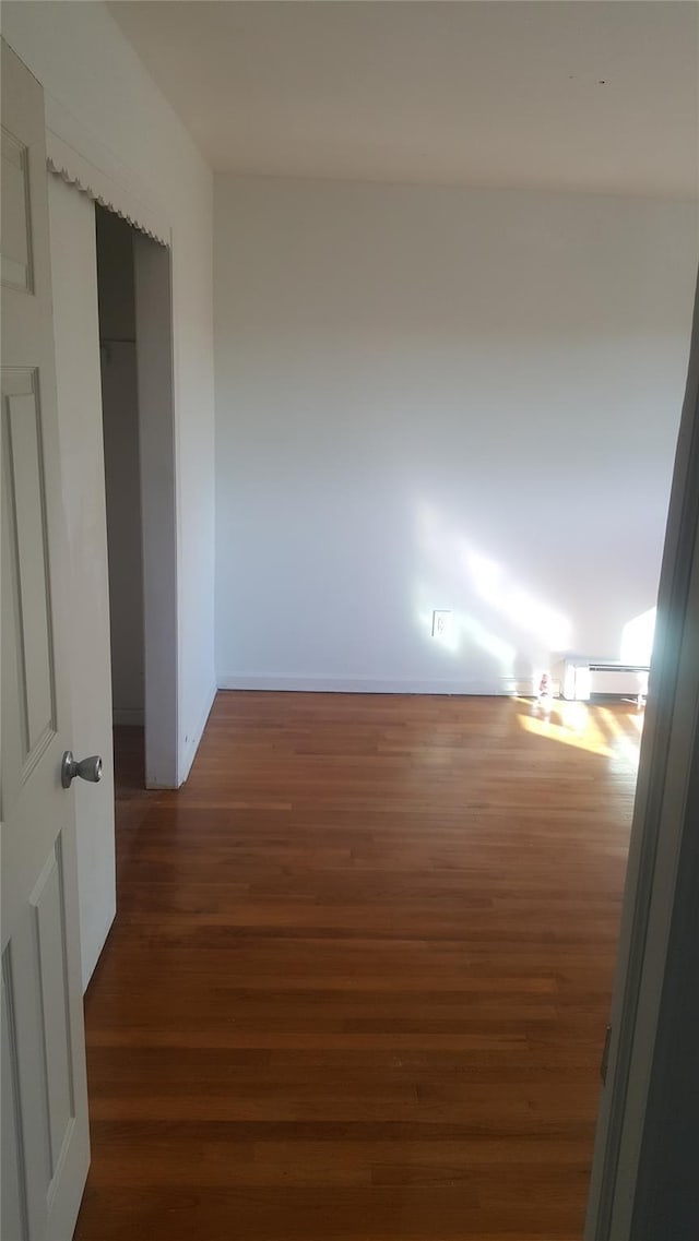 corridor with dark hardwood / wood-style floors and a baseboard radiator