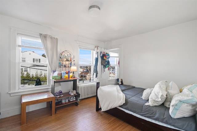 bedroom featuring multiple windows, radiator, and hardwood / wood-style floors