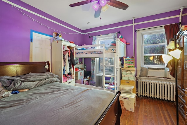 bedroom with dark wood-type flooring, radiator heating unit, ceiling fan, and cooling unit