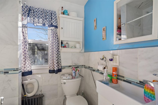 bathroom featuring tile walls, radiator, and toilet