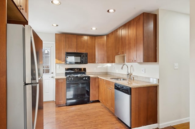 kitchen with sink, light hardwood / wood-style flooring, and black appliances