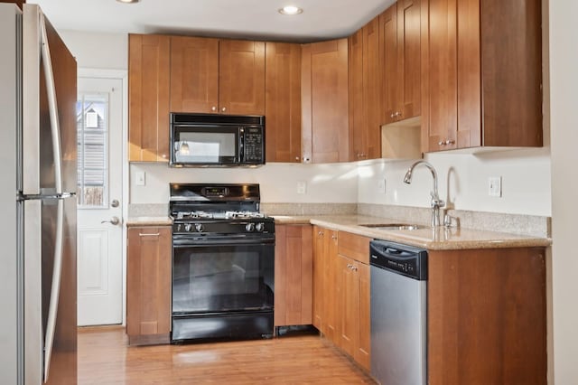 kitchen with sink, black appliances, and light hardwood / wood-style flooring