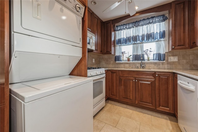 kitchen featuring light tile patterned flooring, white appliances, stacked washer and clothes dryer, and backsplash