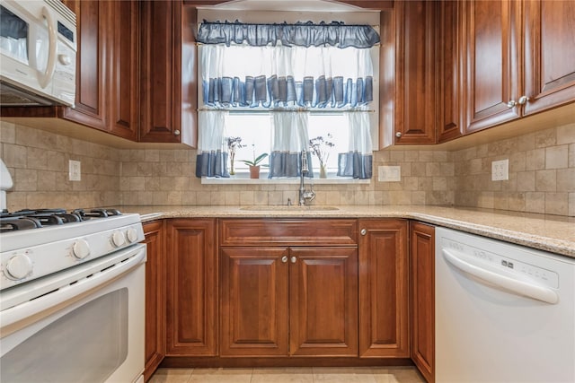 kitchen with white appliances, backsplash, sink, light stone countertops, and light tile patterned floors