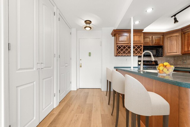 kitchen with decorative backsplash, light hardwood / wood-style floors, stainless steel range oven, and sink