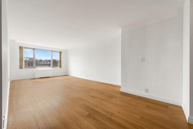 empty room with radiator heating unit and light hardwood / wood-style flooring