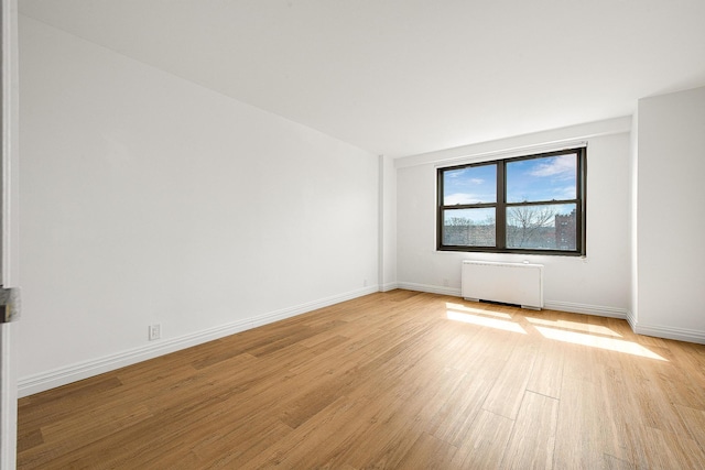 spare room featuring radiator and light wood-type flooring