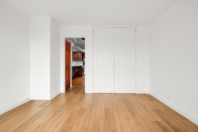 unfurnished bedroom with light wood-type flooring and a closet