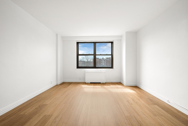 unfurnished room with light wood-type flooring and radiator heating unit