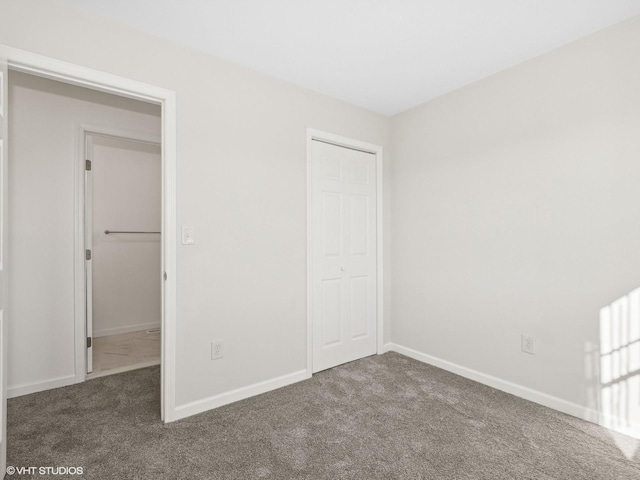 unfurnished bedroom with dark colored carpet and a closet