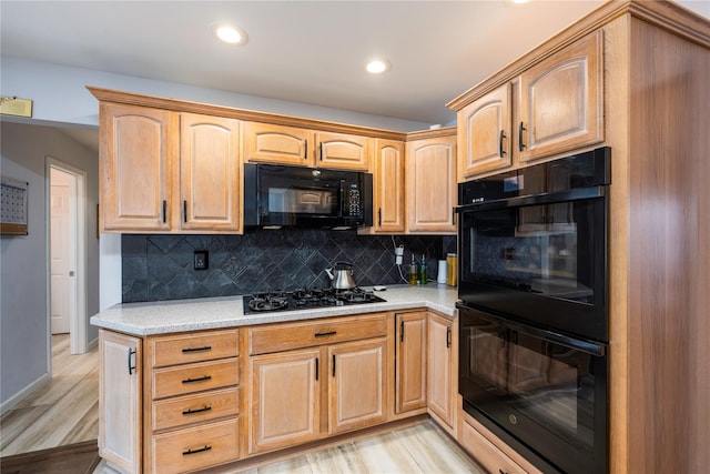 kitchen featuring decorative backsplash, light hardwood / wood-style floors, and black appliances