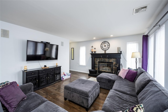 living room with dark wood-type flooring and a tiled fireplace