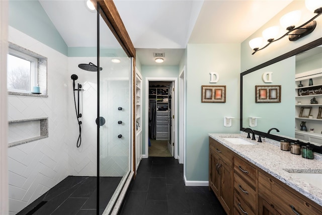 bathroom with tiled shower, vanity, vaulted ceiling, and tile patterned floors