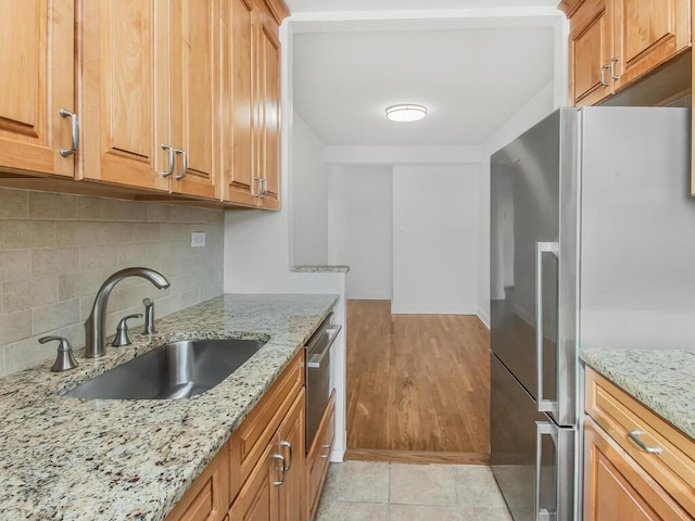 kitchen featuring light stone countertops, sink, light wood-type flooring, and appliances with stainless steel finishes