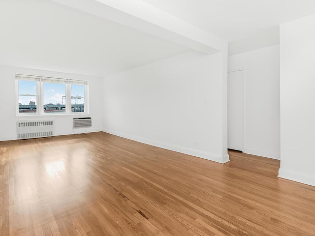 unfurnished living room featuring light wood-type flooring, radiator, and an AC wall unit