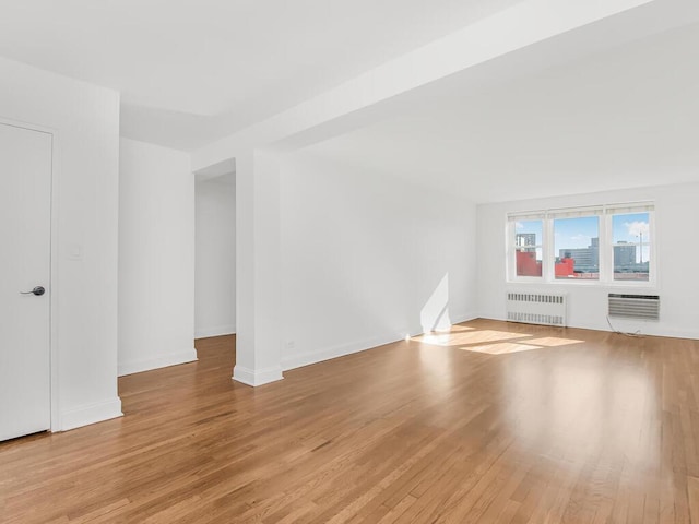 unfurnished living room with an AC wall unit, radiator heating unit, and light hardwood / wood-style flooring